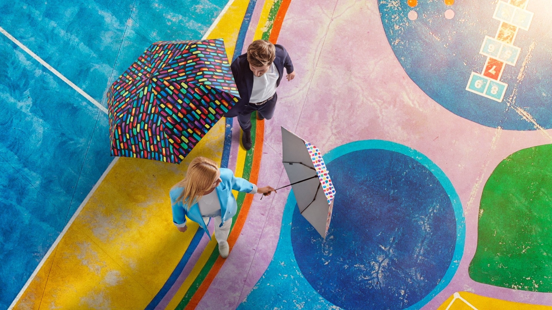 two people on colorful ground with stylish umbrellas two people on colorful ground with stylish umbrellas